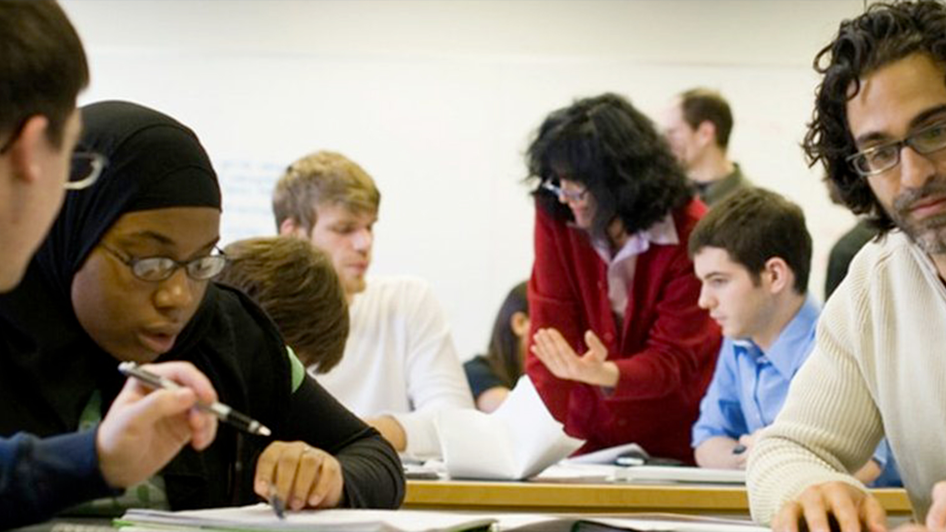 Diverse students sitting at a table working on an assignment.